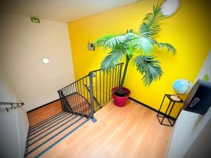 a staircase with a palm tree in a yellow wall at Unisotel Montauban EX F1 in Montauban +17 photos