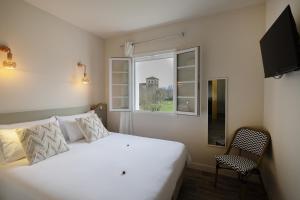 a bedroom with a white bed and a window at Lo Berge in Saint-Pée-sur-Nivelle