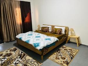 a bedroom with a bed and two rugs at L'évasion-Royale in Thiès