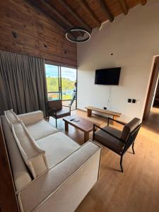 a living room with a couch and chairs and a tv at Lagoa by Loop in Horizonte