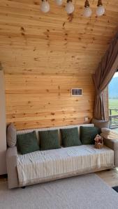 a couch in a room with a wooden wall at ALAU villas in Saty