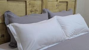 a bed with two white pillows and a wooden headboard at CJ Apartments in Kapchorwa