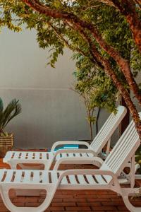 two white lounge chairs sitting under a tree at Pousada Nanai in Foz do Iguaçu