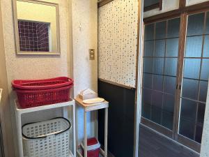 a small bathroom with a door and baskets on a shelf at YADOease in Tsuiki +25 photos