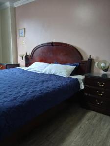 ein Schlafzimmer mit einem blauen Bett mit hölzernem Kopfteil in der Unterkunft Hotel Jomaley in Loja