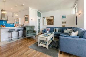 a living room with a blue couch and a kitchen at 4 Bed in Looe oc-l30051 in Looe +26 photos