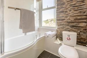 a bathroom with a white toilet and a stone wall at 4 Bed in Looe oc-l30051 in Looe