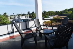 three chairs and a table on a balcony with a view at Lasya Residence in Trincomalee