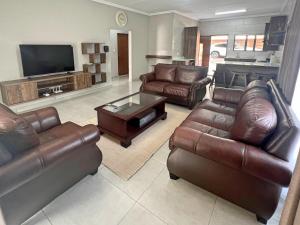 a living room with leather furniture and a flat screen tv at Vaendzi Lodge in Nelspruit +21 photos
