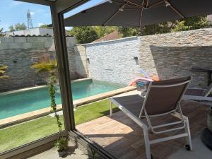 a patio with a chair and an umbrella and a swimming pool at Evasion Suite parentale in La Couronne