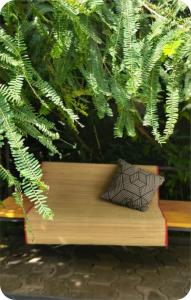 a wooden bench with a pillow in front of a plant at The bharani villa in Pulpally