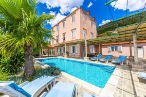 a villa with a swimming pool and a palm tree at Villa Adriatic Pearl in Dubrovnik