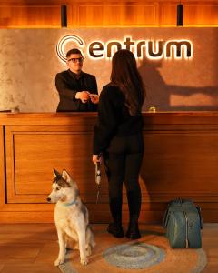 a woman and a man with a dog at a counter at Hotel Centrum Prizren in Prizren