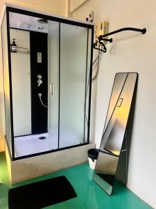 a glass shower in a room with a mirror at arakhouse อารักษ์เฮ้าส์ in Godown