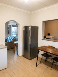a kitchen with a stainless steel refrigerator and a table at Die Ou Lady - Dwarskersbos in Velddrif