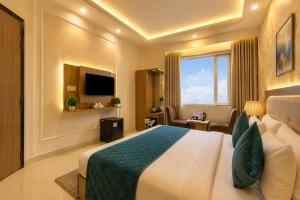a hotel room with a bed and a television at The Grand Olive Aero Suites Near Delhi Airport in New Delhi