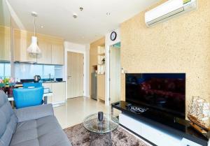 a living room with a couch and a tv and a kitchen at Grande Carribean apartments Jomtien beach Pool view Sea View in Pattaya South