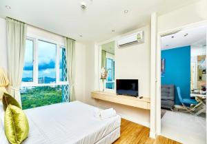 a bedroom with a bed and a large window at Grande Carribean apartments Jomtien beach Pool view Sea View in Pattaya South