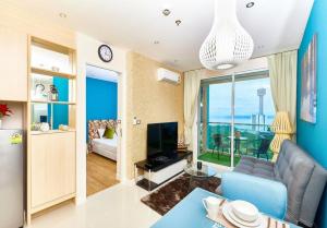 a living room with a blue couch and a television at Grande Carribean apartments Jomtien beach Pool view Sea View in Pattaya South