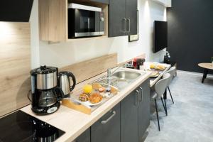 a kitchen with a sink and a counter with food on it at Studio Le Quartz tout inclus petitdéjeuner in Éloyes