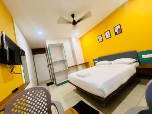 a bedroom with a white bed and a yellow wall at Cozy Rooms & Dormitory in Kozhikode