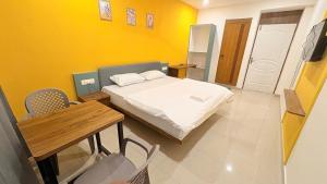 a bedroom with a bed and a table and yellow walls at Cozy Rooms & Dormitory in Kozhikode +10 photos