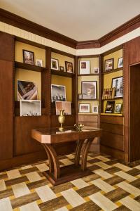 a room with a desk and a wall with pictures at Hôtel Madison in Paris
