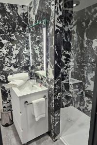 a black and white bathroom with a sink and a shower at Studio Le Cristal tout inclus petitdéjeuner in Éloyes +14 photos