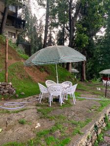 a table and chairs with an umbrella in a yard at The Jasmine House - Ayubia in Ayubia