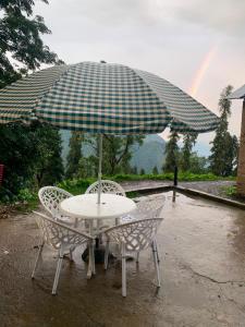 a table and chairs under an umbrella with a rainbow at The Jasmine House - Ayubia in Ayubia