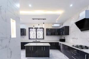 a white kitchen with black cabinets and a sink at Cees Place in Ogbojo
