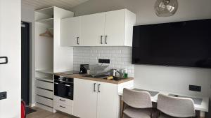 a kitchen with white cabinets and a tv on the wall at Landbrot Guesthouse in Kirkjubæjarklaustur
