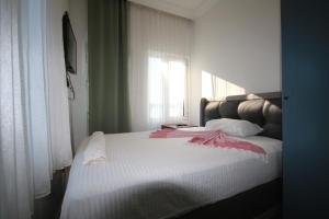 a bedroom with a bed with white sheets and a window at Okan Ali Gürsoy Otel in Ayvalık