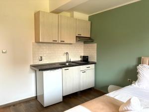 a kitchen with white cabinets and a sink next to a bed at Boho House Florina in Florina