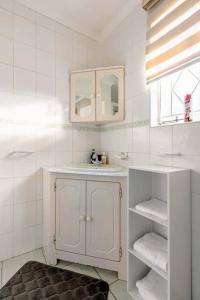 a white bathroom with a sink and a mirror at Hephzibah Manor in Alberton +21 photos