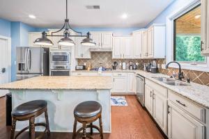 a kitchen with white cabinets and a large island with two bar stools at The Blue Crown Manor at Concord Estates in Concord