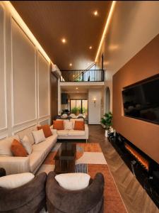 a living room with couches and a flat screen tv at The Courtyard Heritage Pool Villa Udonthani in Udon Thani