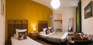a bedroom with two beds and a yellow wall at Hôtel Du Palais Bastia Centre in Bastia