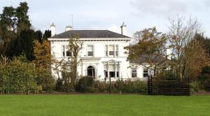 a white house with a fence in front of a yard at Ballinwillin House in Mitchelstown