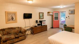 a room with a couch and a tv and a table at Top Notch Motel in Wiarton