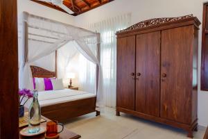 a bedroom with a canopy bed and a wooden cabinet at Kasitha Ocean View Villa - Matara Beach Road in Matara