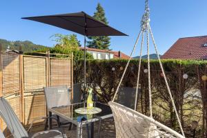 a patio with a table and chairs and an umbrella at Am Silberbergblick in Bodenmais