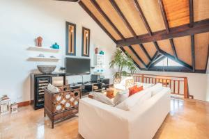 a living room with a white couch and a tv at Gorgeous PH at Puerto Bahia in Santa Bárbara de Samaná