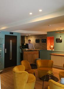 a man standing at a counter in a room with chairs at Hotel Molière in Cannes