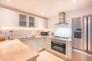 a kitchen with white cabinets and a stainless steel refrigerator at 3BR Beachfront townhouse at Puerto Bahia in Santa Bárbara de Samaná
