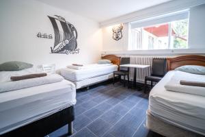 ein Zimmer mit drei Betten, einem Tisch und einem Fenster in der Unterkunft Selfoss Hostel in Selfoss