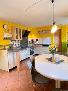 a kitchen with yellow walls and a table and chairs at Dat Uhlenhus in Bohlsen