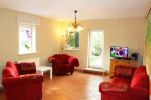 a living room with red chairs and a tv at Dat Uhlenhus in Bohlsen