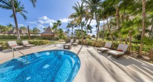 a swimming pool with chaise lounge chairs and palm trees at Dreams Riviera Cancun Resort & Spa - All Inclusive in Puerto Morelos