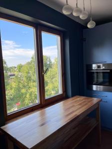 a kitchen with a wooden table and two windows at Aluksne city nest in Alūksne